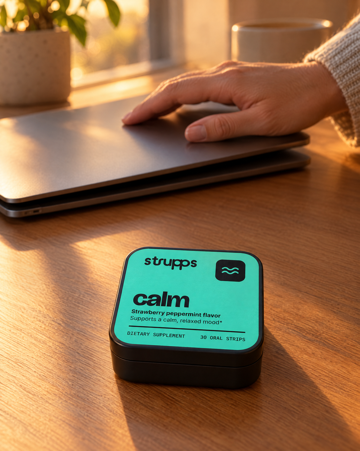 A hand closing a laptop at 5pm beside the strupps Calm tin