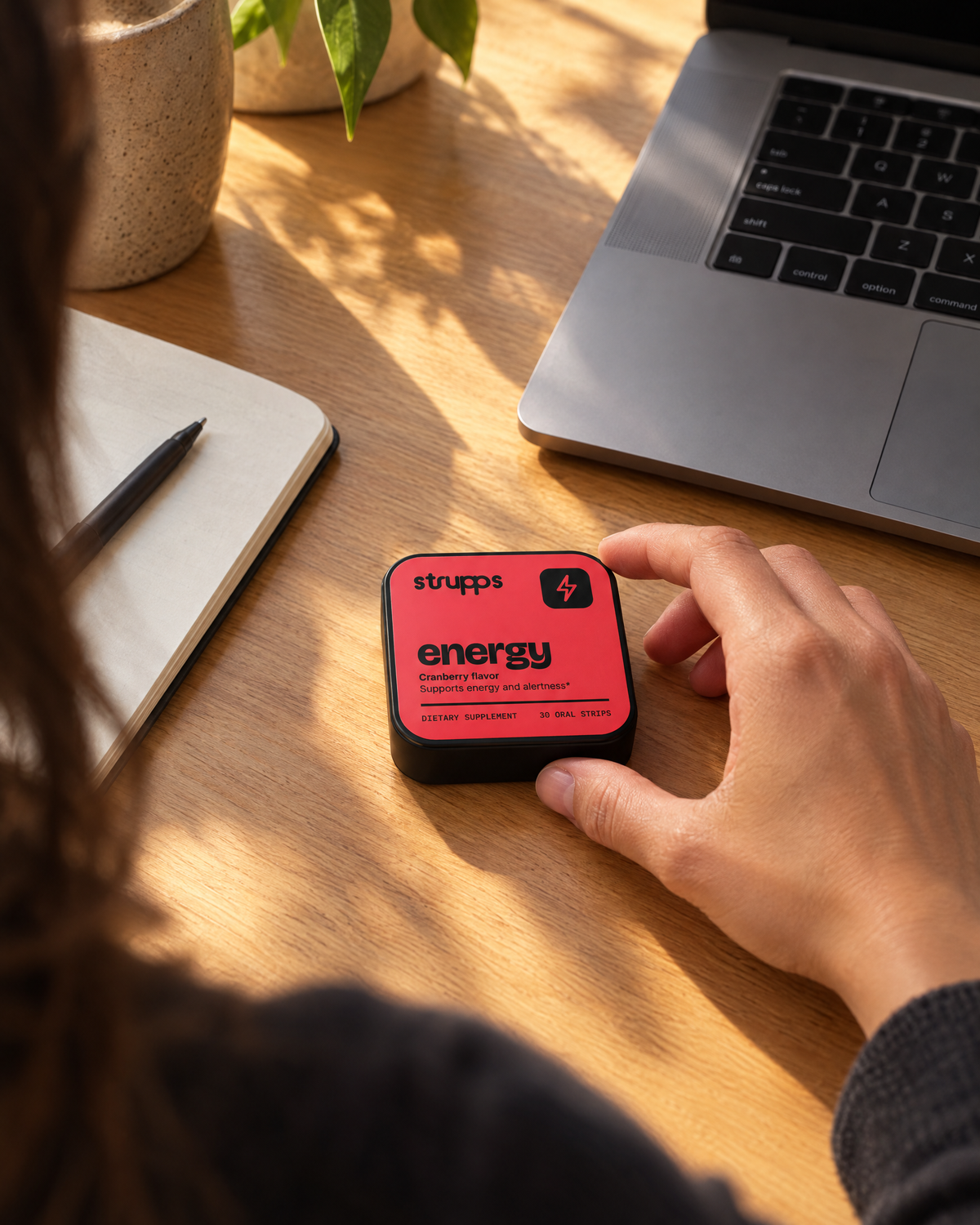 Hand reaching for the strupps Energy tin on a sunny desk in the afternoon