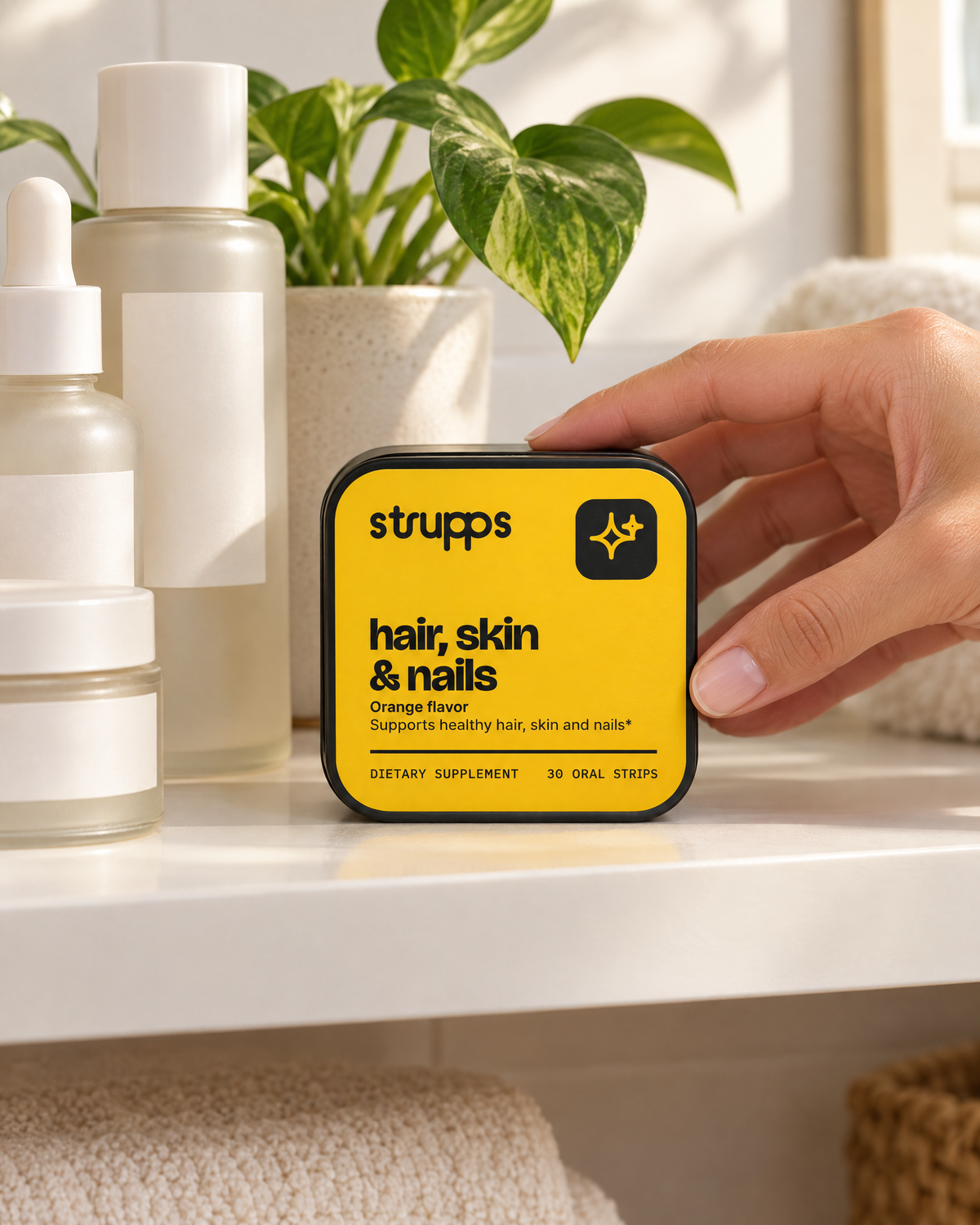 A hand placing the strupps Hair, Skin and Nails tin on a bathroom shelf